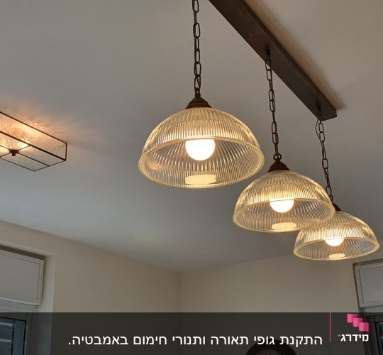 שלושה גופי תאורה תלויים עם נורות דולקות